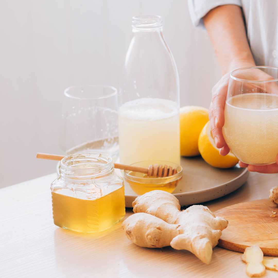 ginger, a glass with honey, a lemon and a glass of lemon juice on a table