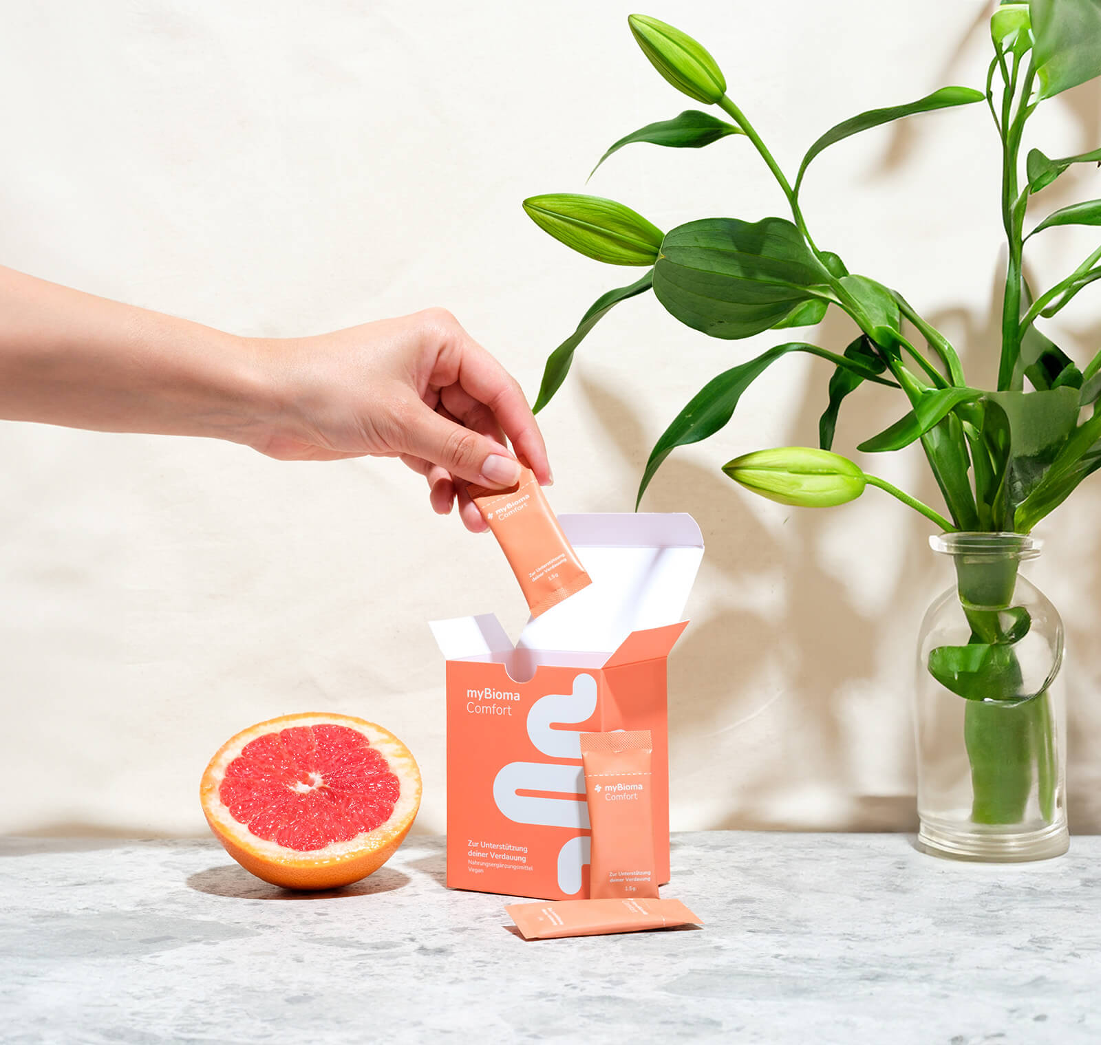 myBioma Comfort Packung mit entnommenem Sachet, weiteres davor liegend, daneben eine Grapefruit.